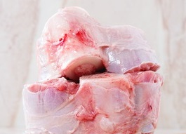 45611141 - stack of raw osso buco meat on crumpled paper with salt, pepper and rosemary over white marble as background